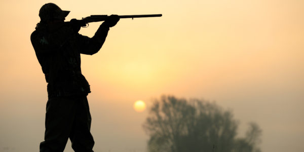 Silhouette of a hunter aiming his shotgun